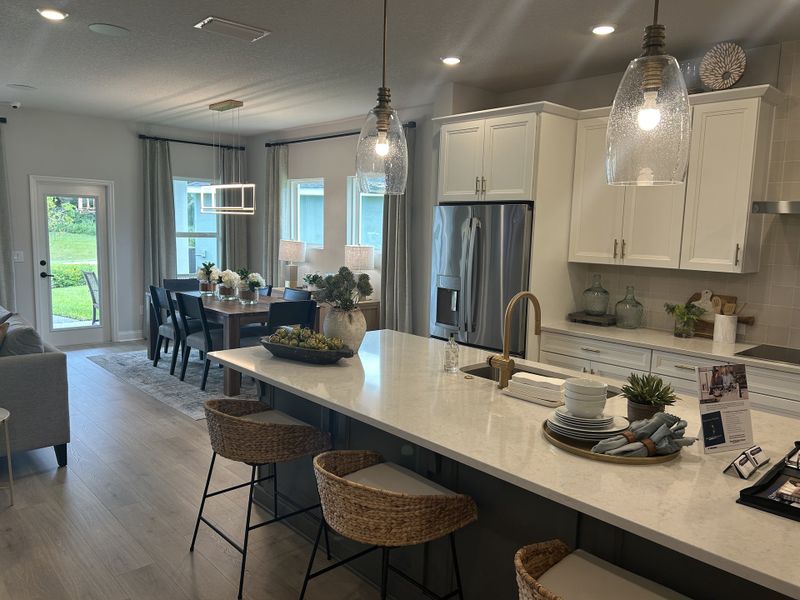 A stylish open-plan kitchen and dining area with modern lighting, sleek appliances, and elegant decor.