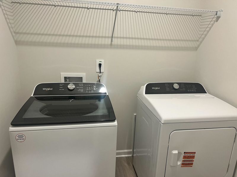 A modern laundry room featuring a sleek washer and dryer set beneath a practical wire shelf. A modern laundry room featuring a sleek washer and dryer set beneath a practical wire shelf.