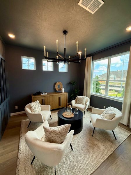 A cozy sitting room with plush white chairs, a round table, and elegant lighting, featuring a natural wood credenza. A cozy sitting room with plush white chairs, a round table, and elegant lighting, featuring a natural wood credenza.
