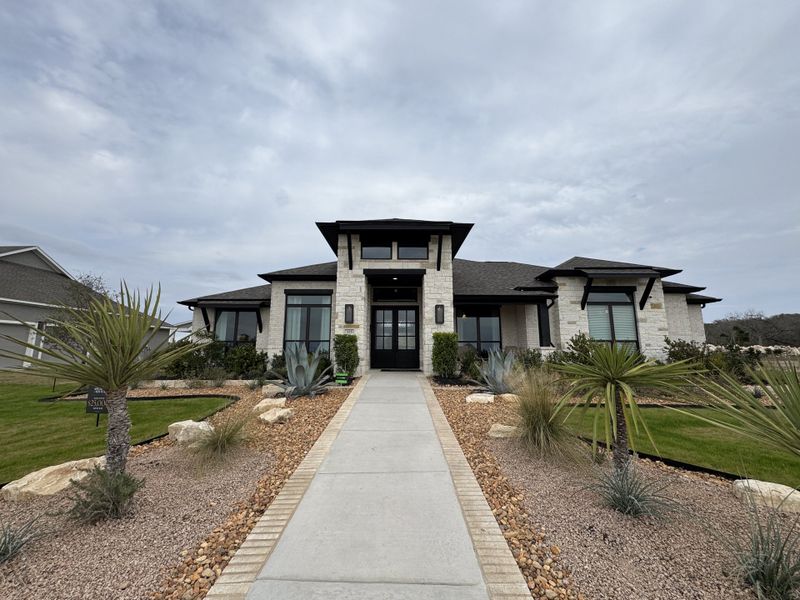 A modern stone home with sleek black accents and a manicured desert landscape in Megan's Landing Half Acre by Perry Homes (San Antonio, TX). A modern stone home with sleek black accents and a manicured desert landscape in Megan's Landing Half Acre by Perry Homes (San Antonio, TX).
