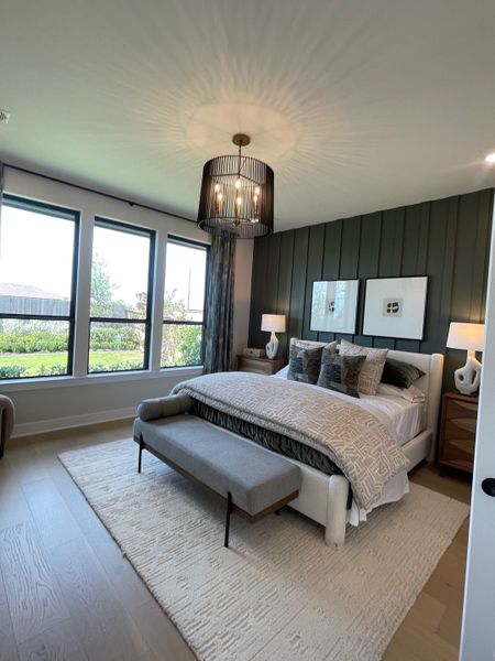 A chic bedroom with a statement chandelier, large windows, cozy bedding, and an elegant bench on a plush rug. A chic bedroom with a statement chandelier, large windows, cozy bedding, and an elegant bench on a plush rug.