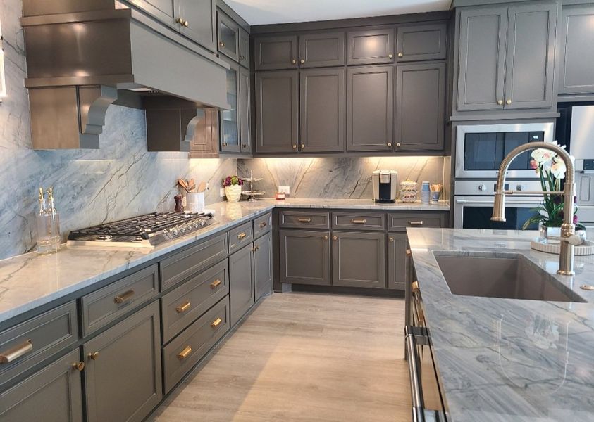 A luxurious kitchen with sleek gray cabinets, marble countertops, and modern appliances.