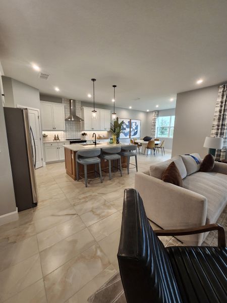 An open-concept kitchen and living area with elegant lighting, modern furnishings, and sleek tile flooring.