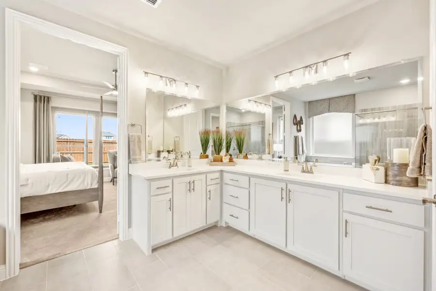 Master bathroom with dual vanities, white cabinets, large mirrors, and open view into the bedroom. Master bathroom with dual vanities, white cabinets, large mirrors, and open view into the bedroom.