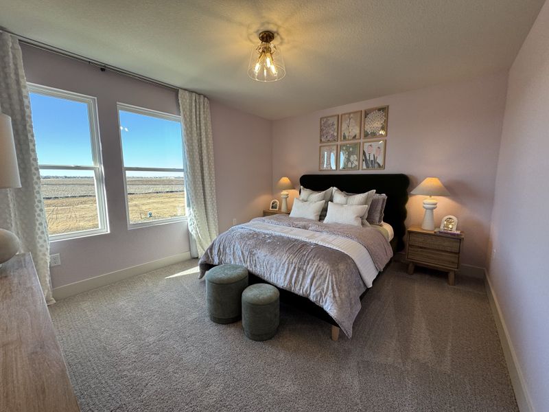 A cozy bedroom featuring soft pink walls, a plush bed, natural light, and elegant decor for a serene ambiance.