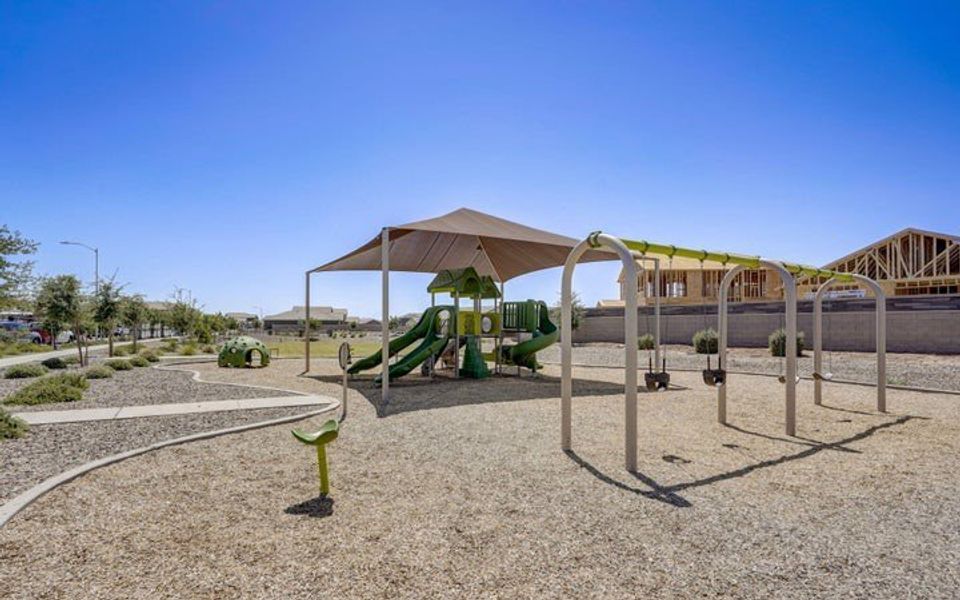 A vibrant playground with shade in Villages at Accomazzo by Starlight Homes, Tolleson, AZ, perfect for family fun.
