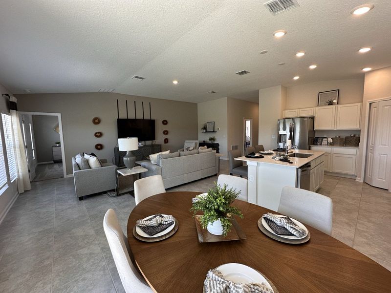 Open-concept living area with a cozy lounge, elegant dining table, and modern kitchen featuring sleek cabinetry and stainless appliances. Open-concept living area with a cozy lounge, elegant dining table, and modern kitchen featuring sleek cabinetry and stainless appliances.