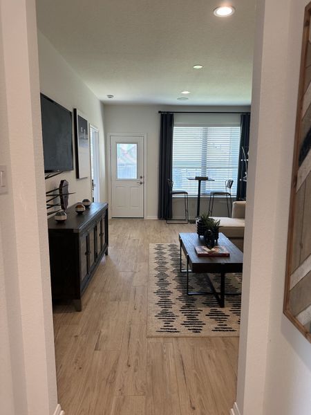 A cozy living area with wood flooring, a patterned rug, modern furnishings, and ample natural light through large windows. A cozy living area with wood flooring, a patterned rug, modern furnishings, and ample natural light through large windows.