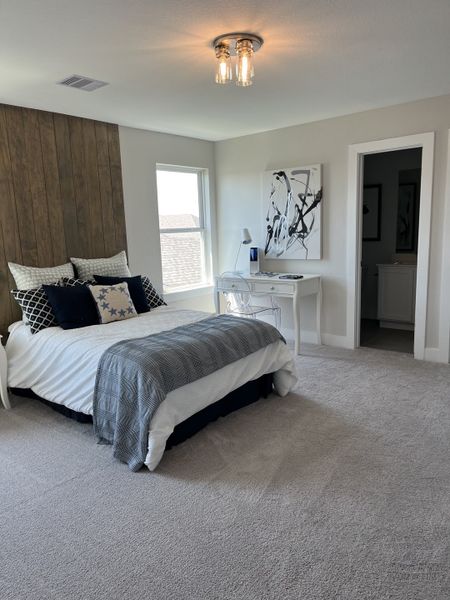 A cozy bedroom featuring soft carpet, a wood accent wall, modern lighting, and a sleek desk for a stylish touch.