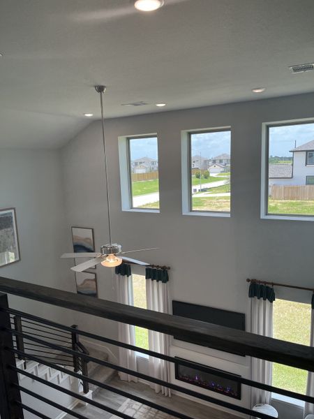 A bright living room with large windows, white curtains, and a modern ceiling fan, offering natural light and elegance. A bright living room with large windows, white curtains, and a modern ceiling fan, offering natural light and elegance.