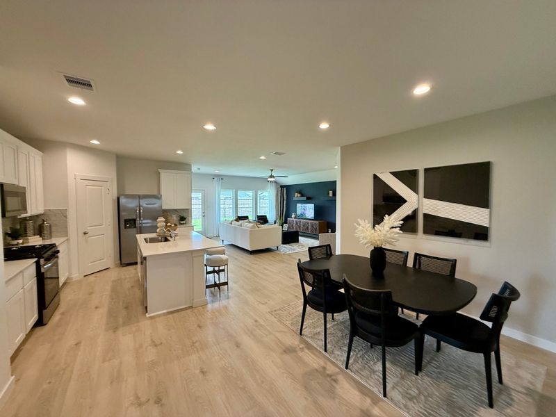 Open-concept living area with sleek kitchen, island seating, contemporary dining, and cozy living room.