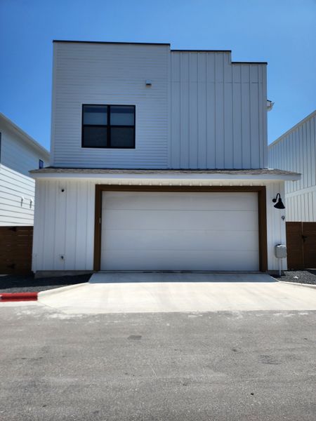 A sleek modern white home with a flat roof and a large garage in Coopers Square by Legacy Communities (Austin, TX).