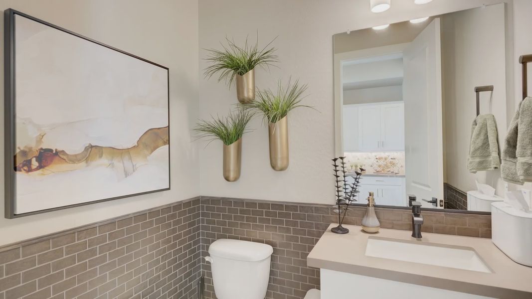 This exquisite bathroom boasts sophisticated wall-mounted art, modern fixtures, and rich brick tile in Arroyo Seco.