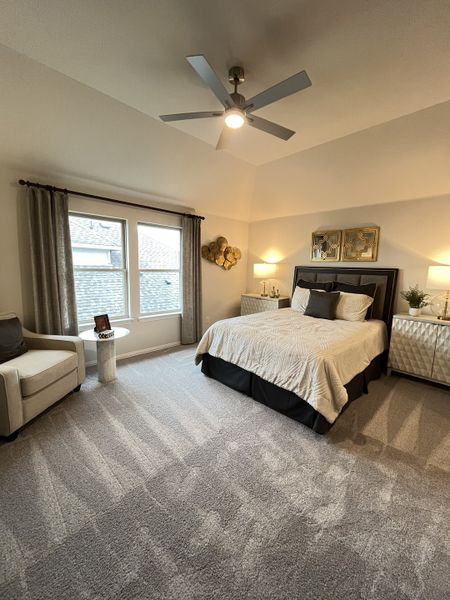 A spacious bedroom featuring cozy carpeting, a stylish bed, accent chair, and elegant decor with ample natural light.