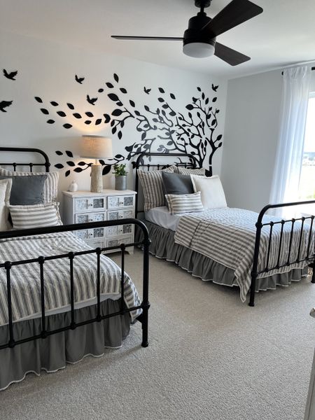 A charming bedroom with twin beds, artistic wall decals, and cozy lighting for a serene atmosphere.