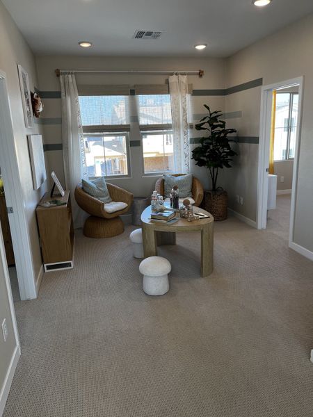 Relaxing nook with woven chairs, soft rugs, and playful stools, bathed in natural light from large windows.