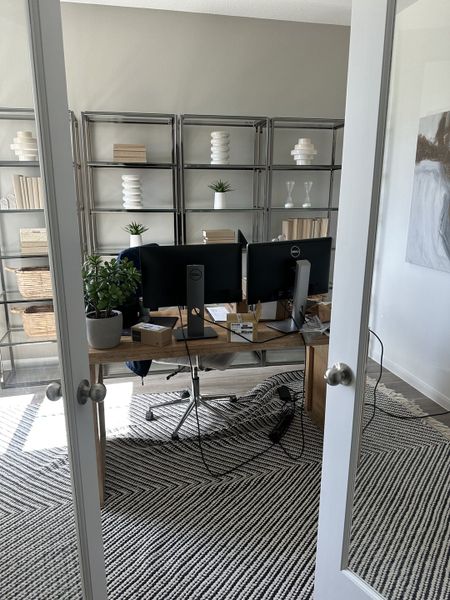 A modern home office with sleek shelving, dual monitors, and a stylish striped rug. Cozy and functional workspace.