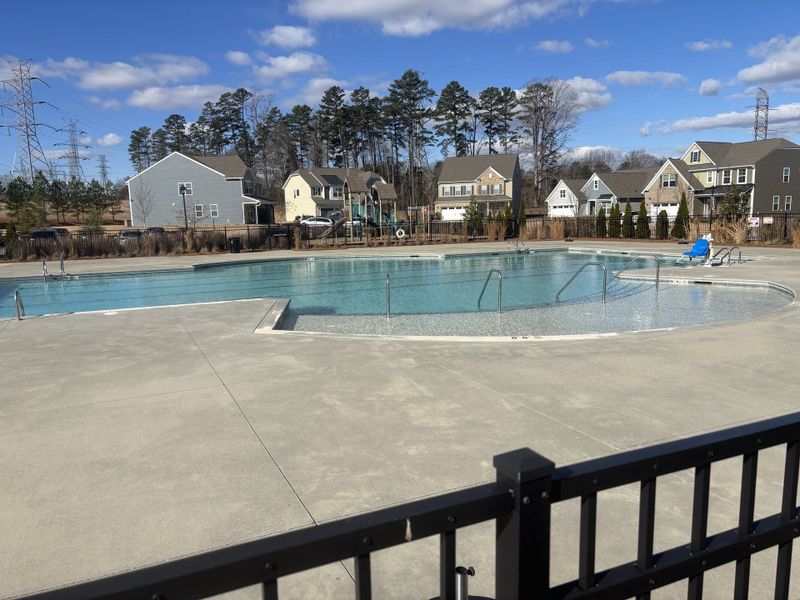 Community pool area with surrounding modern homes and playground in Bryton by Pulte Homes (Huntersville, NC).