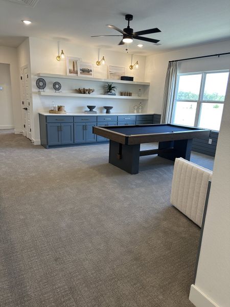 A stylish game room with a modern pool table, blue cabinetry, and sleek lighting features. A stylish game room with a modern pool table, blue cabinetry, and sleek lighting features.