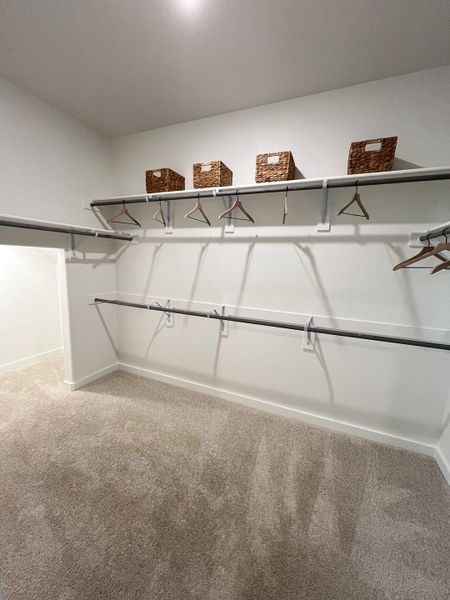 A spacious walk-in closet with plush carpeting, shelving, and hanging space. Perfect for organized storage. A spacious walk-in closet with plush carpeting, shelving, and hanging space. Perfect for organized storage.