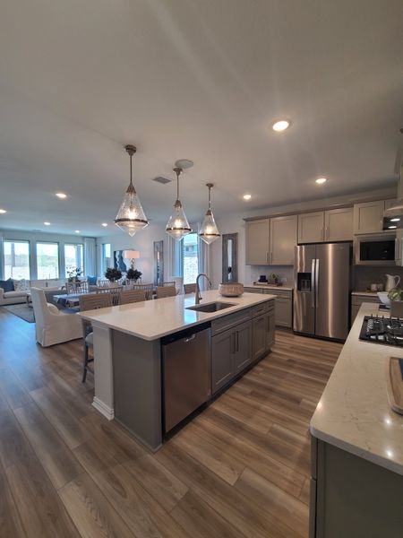 A modern kitchen with elegant pendant lighting, a spacious island, and stainless steel appliances.