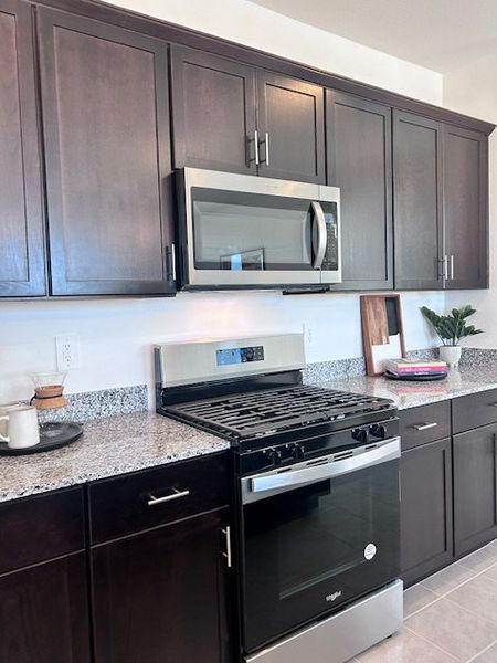 A sleek kitchen featuring dark wood cabinets, granite countertops, and stainless steel appliances for a modern touch. A sleek kitchen featuring dark wood cabinets, granite countertops, and stainless steel appliances for a modern touch.
