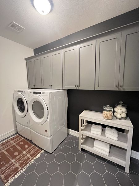A modern laundry room featuring sleek cabinets, hexagonal tile flooring, and efficient white appliances. A modern laundry room featuring sleek cabinets, hexagonal tile flooring, and efficient white appliances.