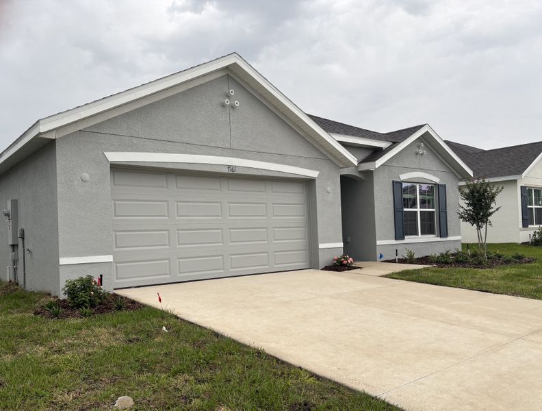 A modern gray home with blue shutters and tidy landscaping in Autumn Glen by D.R. Horton (Belleview, FL).