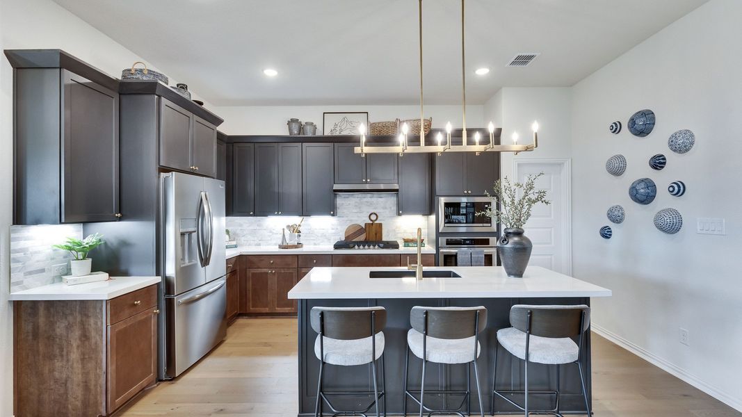 Sophisticated dark cabinetry with brass fixtures and a sleek island elevate this Lakeside Meadows kitchen. Sophisticated dark cabinetry with brass fixtures and a sleek island elevate this Lakeside Meadows kitchen.