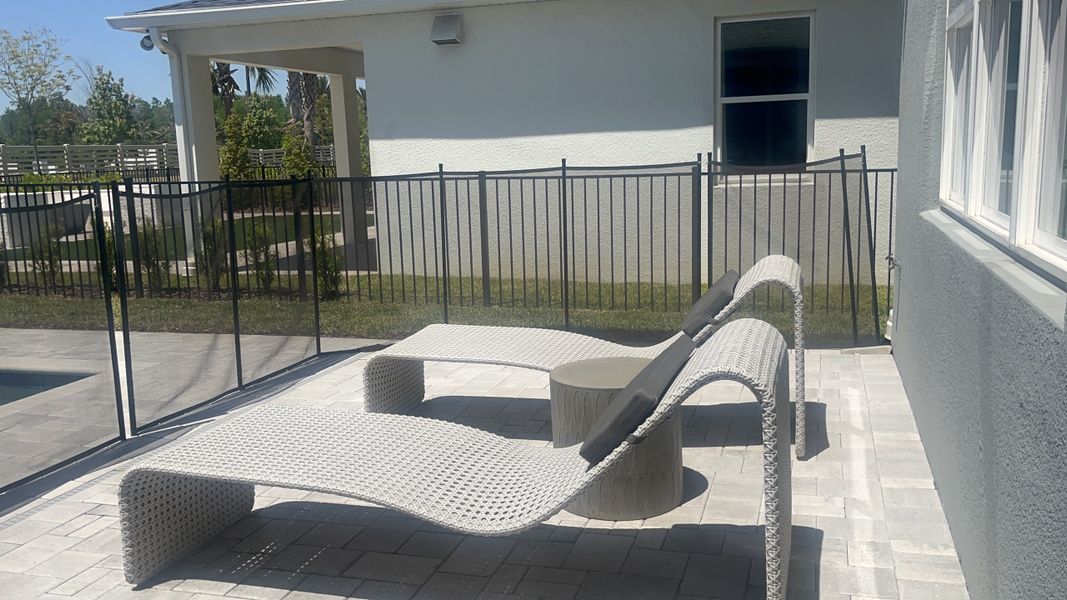 A sunny patio with modern lounge chairs and a sleek fence, perfect for relaxation and outdoor leisure. A sunny patio with modern lounge chairs and a sleek fence, perfect for relaxation and outdoor leisure.