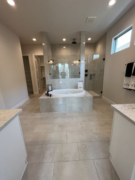 A luxurious bathroom with a central soaking tub, glass shower, and elegant lighting.