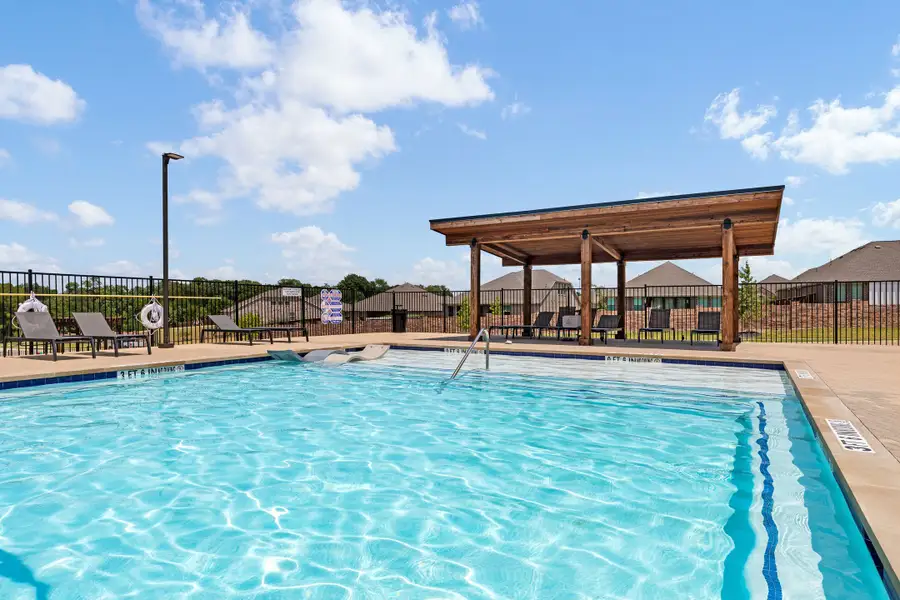 Community pool with wood pergola, lounge chairs, and black iron fence surrounding the deck area