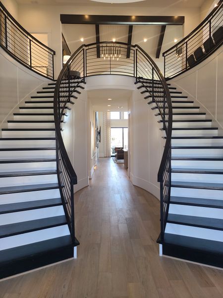 A grand double staircase with elegant railings and a bright open hallway, offering luxurious design and inviting atmosphere.