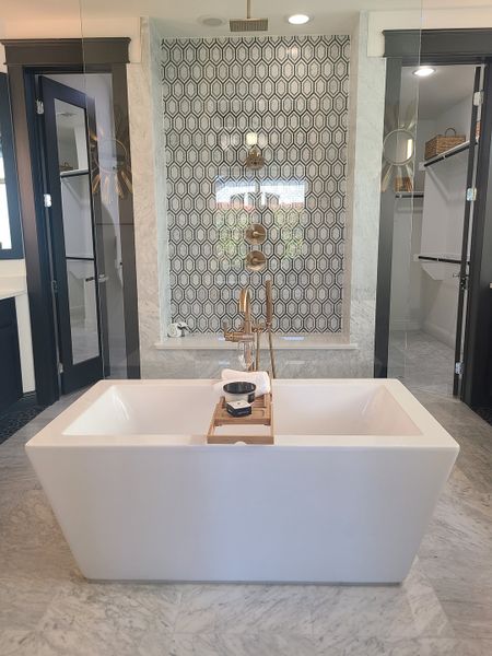 A luxurious bathroom with a freestanding tub, intricate tile accent wall, and marble flooring for a sleek, modern look.