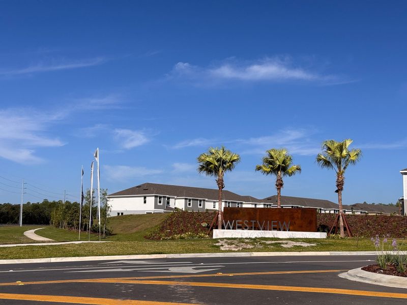 A contemporary community entrance with palm trees at Westview: Overlook Townhomes by Lennar in Kissimmee, FL.