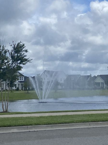Scenic view of a tranquil pond with a fountain and surrounding homes in Seven Pines by ICI Homes (Jacksonville, FL).