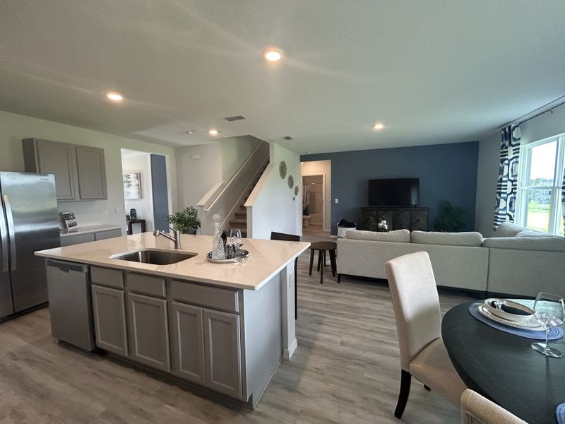 An open-concept living space featuring a modern kitchen with an island, cozy seating area, and elegant dining set.