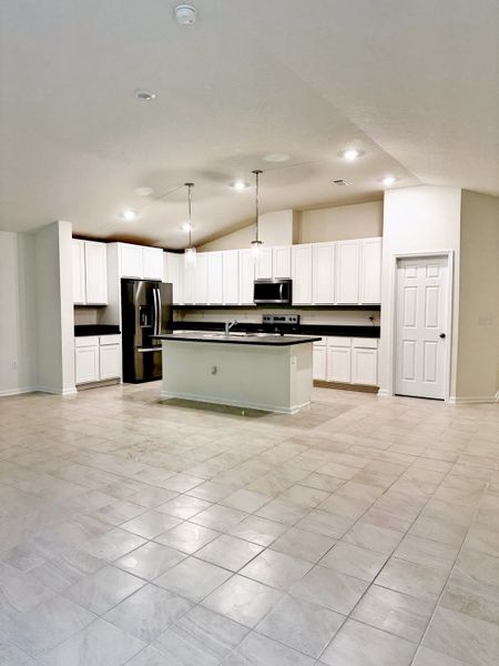 A spacious kitchen with sleek white cabinetry, a central island, and modern stainless steel appliances.