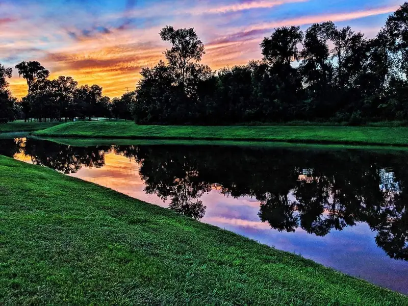 A serene pond at sunset with vibrant skies in Sienna 65' by Shea Homes, Missouri City, TX.