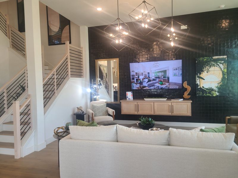 A modern living room with sleek black tile wall, stylish lighting, and elegant staircase. A modern living room with sleek black tile wall, stylish lighting, and elegant staircase.