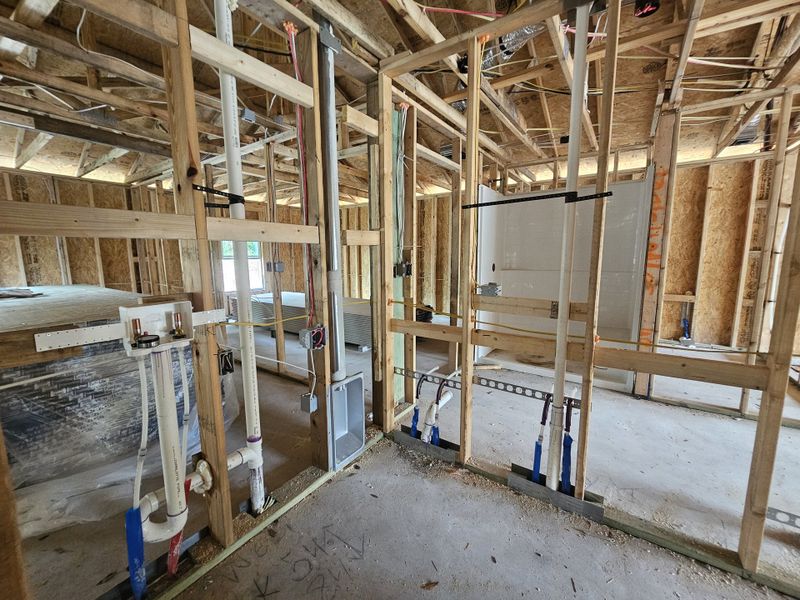 A construction site with exposed framing and plumbing, showcasing the ongoing development of a new home interior.