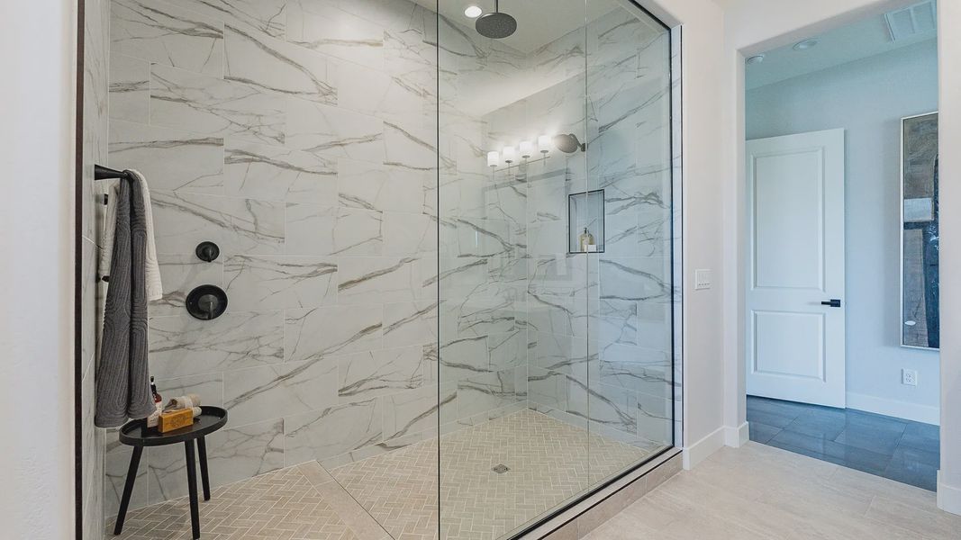 Opulent marble-tiled shower with sleek black fixtures and seamless glass in Windrose community.