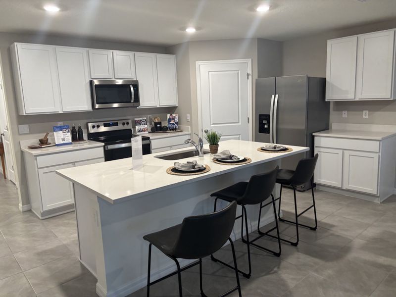 Modern kitchen featuring sleek white cabinets, stainless steel appliances, and a spacious island with bar seating.