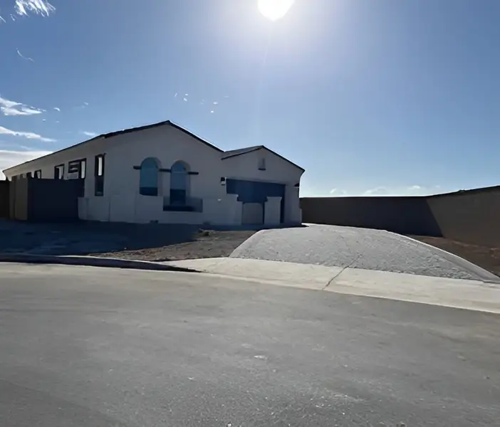 A modern white stucco home with arched windows and a sloped driveway in Grove at Lehi by Blandford Homes (Mesa, AZ).