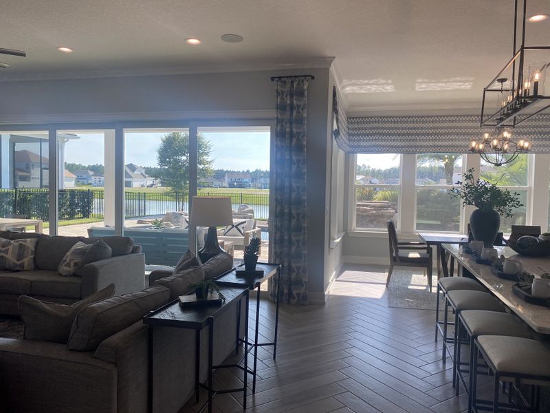 A sunlit living and dining space with lake views, cozy seating, stylish decor, and large windows.