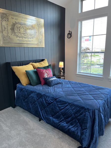 A cozy bedroom featuring a navy quilt, colorful pillows, and a large window with ample natural light. A cozy bedroom featuring a navy quilt, colorful pillows, and a large window with ample natural light.