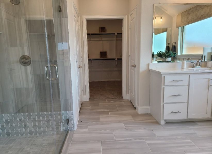 A modern bathroom with a glass shower, dual sinks, and a spacious walk-in closet. A modern bathroom with a glass shower, dual sinks, and a spacious walk-in closet.