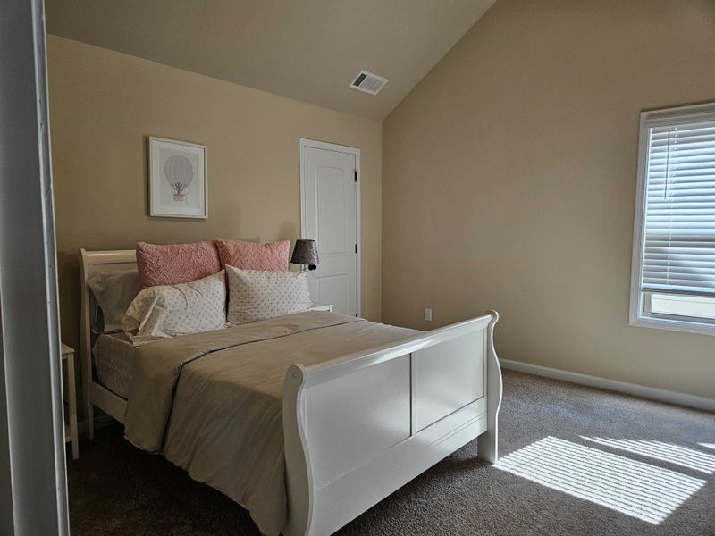 A cozy bedroom with a sloped ceiling, white sleigh bed, and soft pink accents for a serene atmosphere.