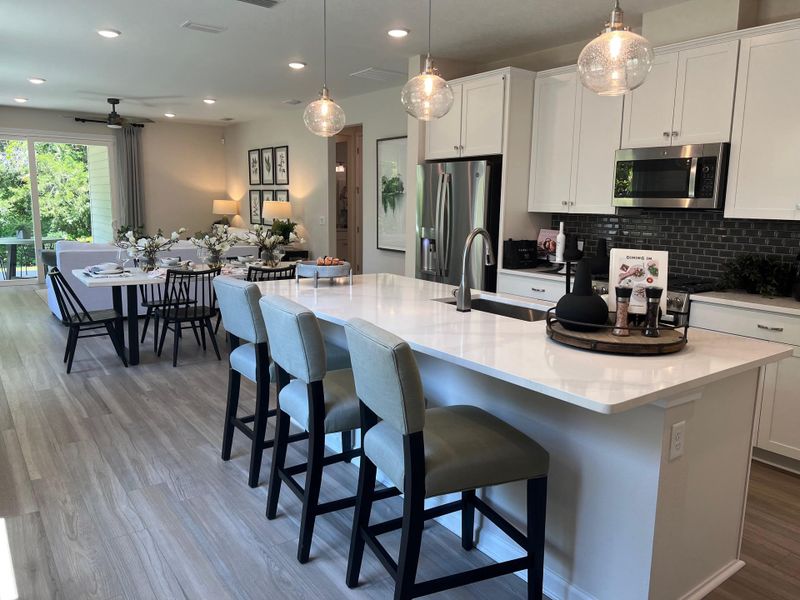 A modern open-concept kitchen and dining area with sleek white cabinetry, elegant island seating, and contemporary decor.