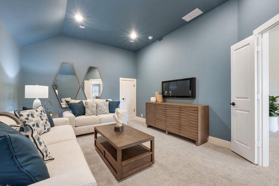Living room with vaulted ceiling, blue walls, sectional sofa, wood coffee table, and wall-mounted TV